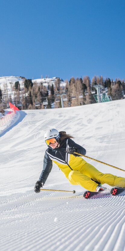 Sciatore in discesa sulla pista Pra di Tori sullo sfondo Latemar | © Carezza Dolomites/Harald Wisthaler