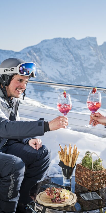 Skiers drinking an aperitif with a view of Latemar | © Carezza Dolomites/Harald Wisthaler