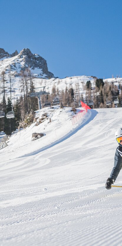 Sciatore in discesa sulla pista Pra di Tori sullo sfondo Latemar | © Carezza Dolomites/Harald Wisthaler