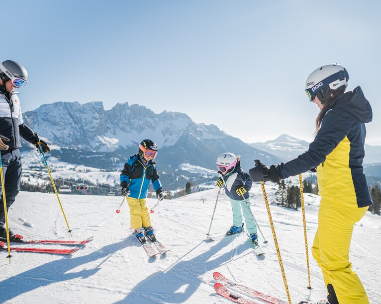 Family skiing with a view of snow-covered Latemar | © Carezza Dolomites/Harald Wisthaler