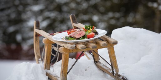 Teller mit Rindsteak und Gemüse auf Schlitten im Schnee | © Günther Pichler