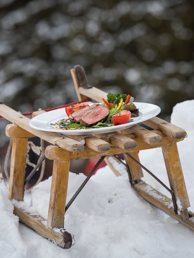 Teller mit Rindsteak und Gemüse auf Schlitten im Schnee | © Günther Pichler