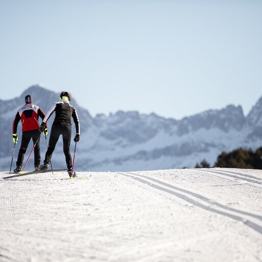 Due sciatori di fondo su una pista perfettamente preparata di Nova Ponente con vista sul Catinaccio | © Eggental Tourismus/Günther Pichler