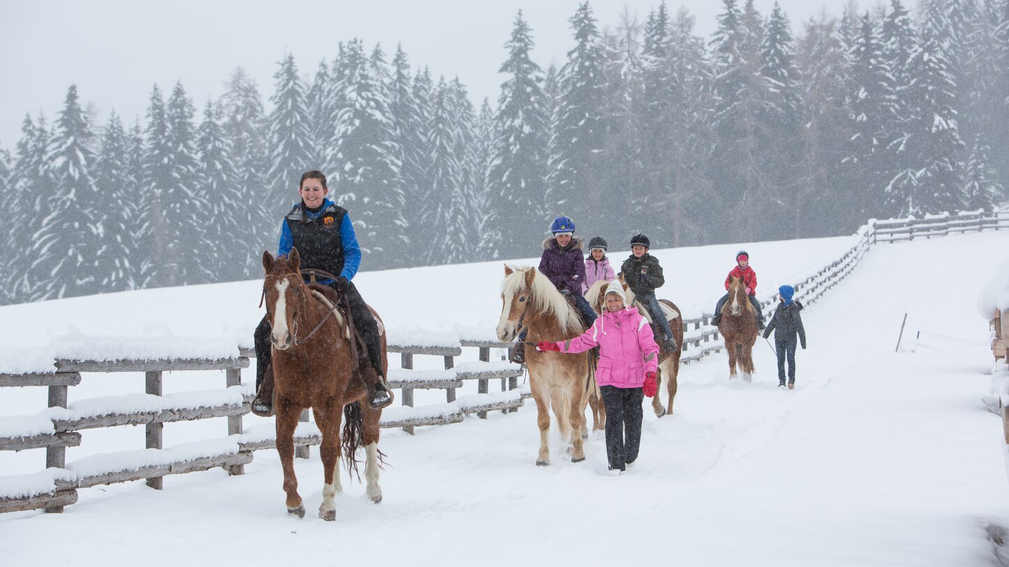 Gruppe von Kindern reitet durch frischen Schnee | © Anerle Alm