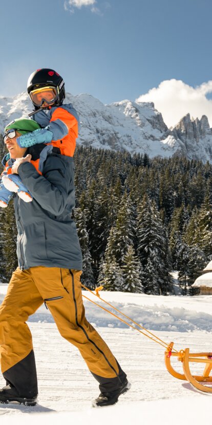 Father and son sledging Latemar view | © Carezza Dolomites/StorytellerLabs
