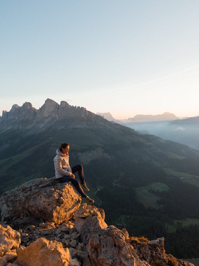 Wandererin sitzt auf einem Felsen mit Blick Richtung Rosengarten | © Thomas Monsorno