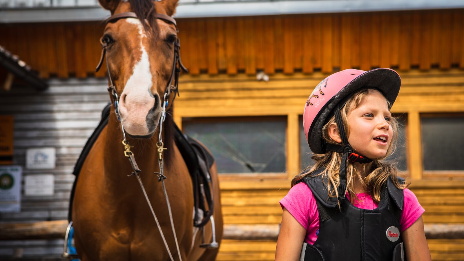 Ragazza cammina accanto a un cavallo marrone  | © Eggental Tourismus/StorytellerLabs