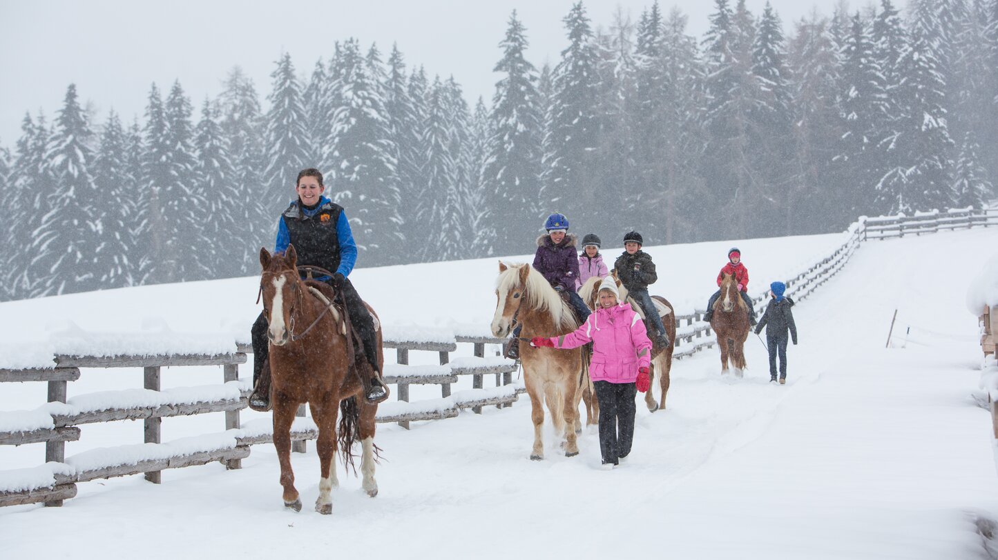 Gruppo di bambini che cavalca sulla neve fresca | © Anerle Alm