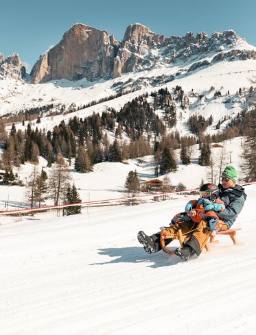 Padre e figlio in slitta inverno Catinaccio | © StorytellerLabs