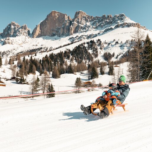 Padre e figlio in slitta inverno Catinaccio | © StorytellerLabs