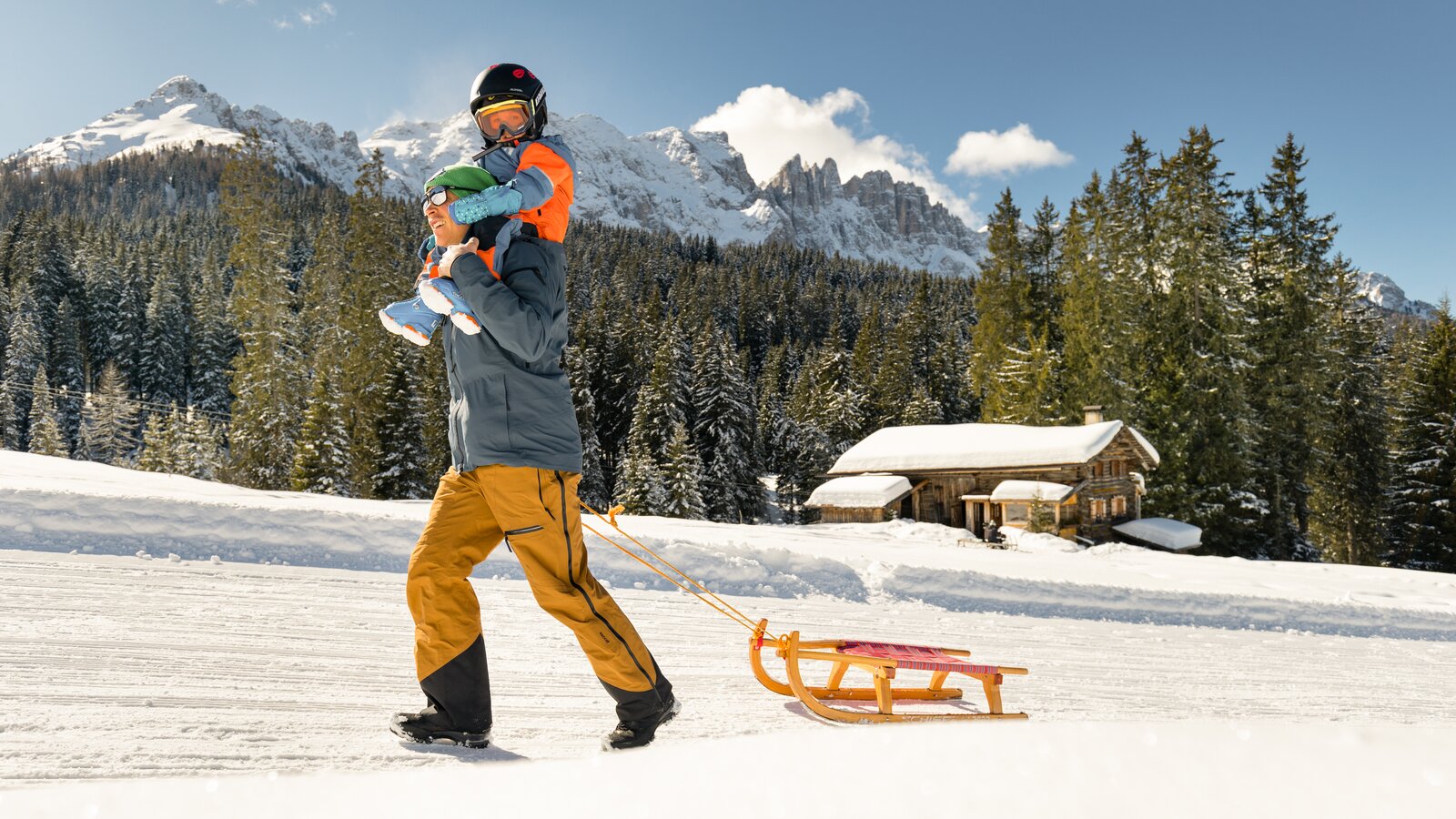 Padre e figlio in slitta vista Latemar | © Carezza Dolomites/StorytellerLabs