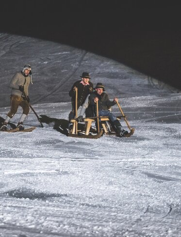uomini con Lederhosen slitta sci da legno | © Ph. Mattia Daldoss